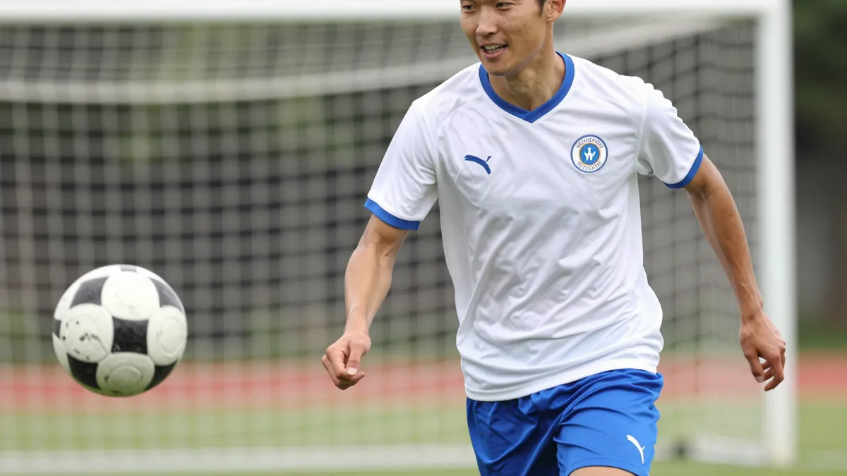 A close-up of a Hvidovre player in a white jersey with blue shorts, running with the ball towards the goal, with a...