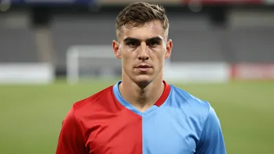Mid-30s Hvidovre forward, athletic build, intense gaze, head-and-shoulders, wearing a plain unmarked home kit split red...